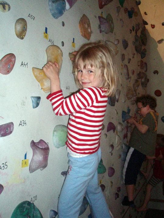 Mädchen klettert konzentriert an der Kletterwand